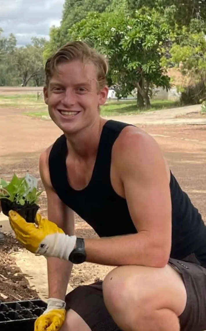 Thomas Hand outdoors, planting seedlings in regional Australia.